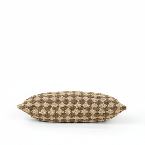 A rectangular throw pillow with a brown and beige geometric diamond pattern, photographed against a solid cream background.