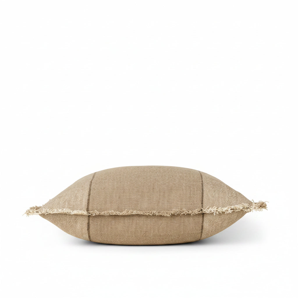A square beige linen throw pillow with a fringed edge and subtle stitched details, set against a solid cream background.
