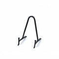 A small black metal display stand with a curved top and two short legs, photographed on a plain warm cream background.