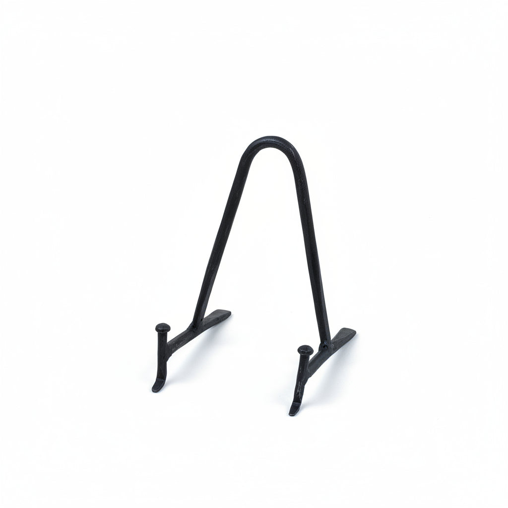 A small black metal display stand with a curved top and two short legs, photographed on a plain warm cream background.